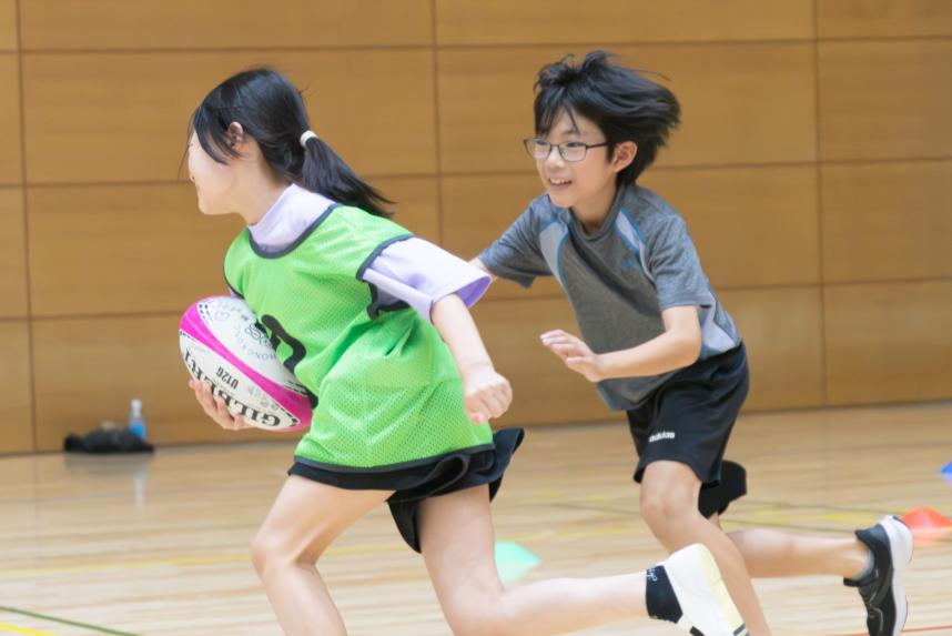 参加児童がラグビーボールを持ち1対1を行い相手を追い抜かす画像