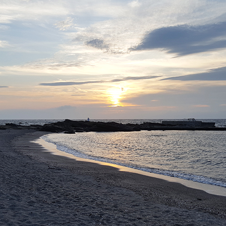 Nakamura Erika smiling in the sea with the sunset in the background
