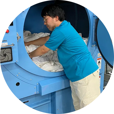 大型ドラム洗濯機を使ってクリーニング作業をする写真