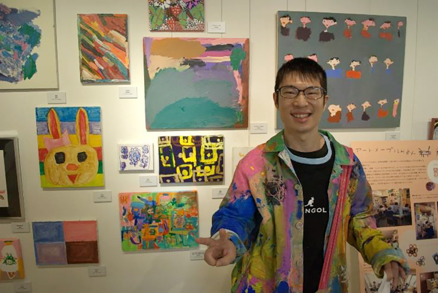 作品「バス タクシー だんご」の前で作家の品川太成さん。上着も自作した作品。